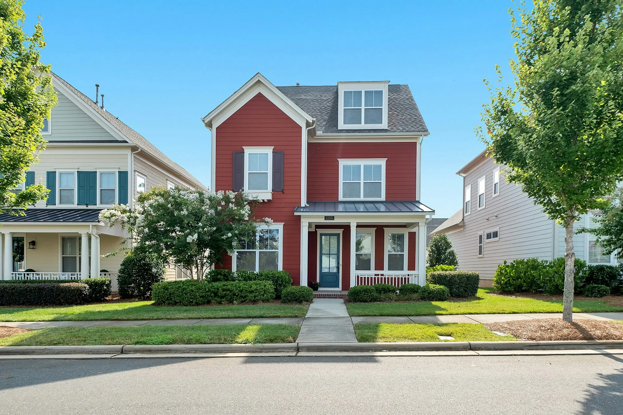 Red two-story house with a front porch on a suburban street