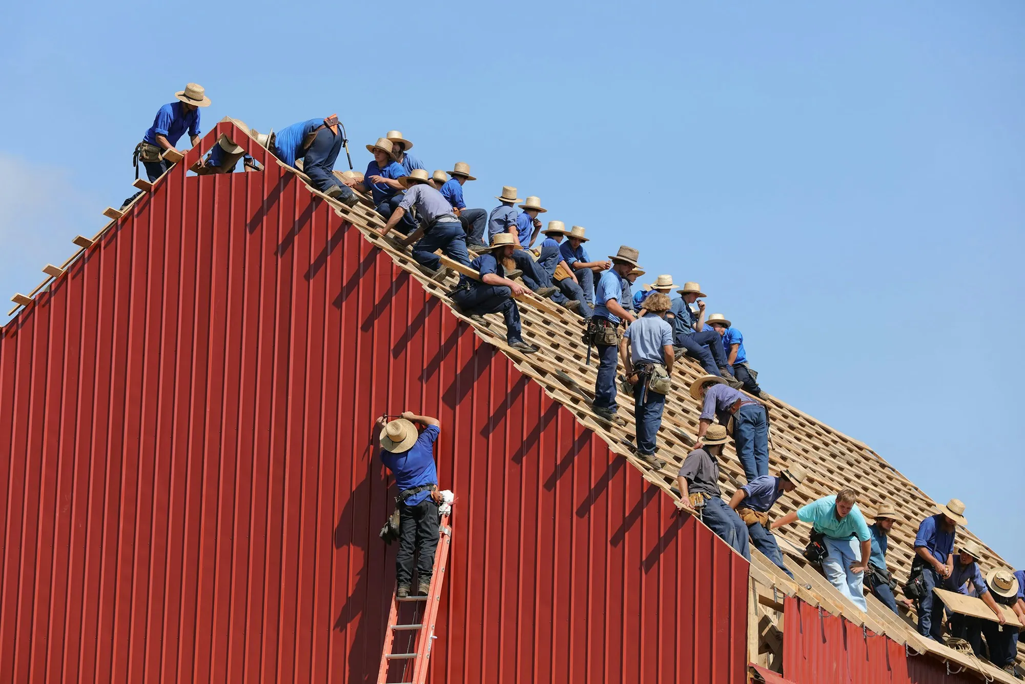 Large roofing crew working along the ridge of a steep roof