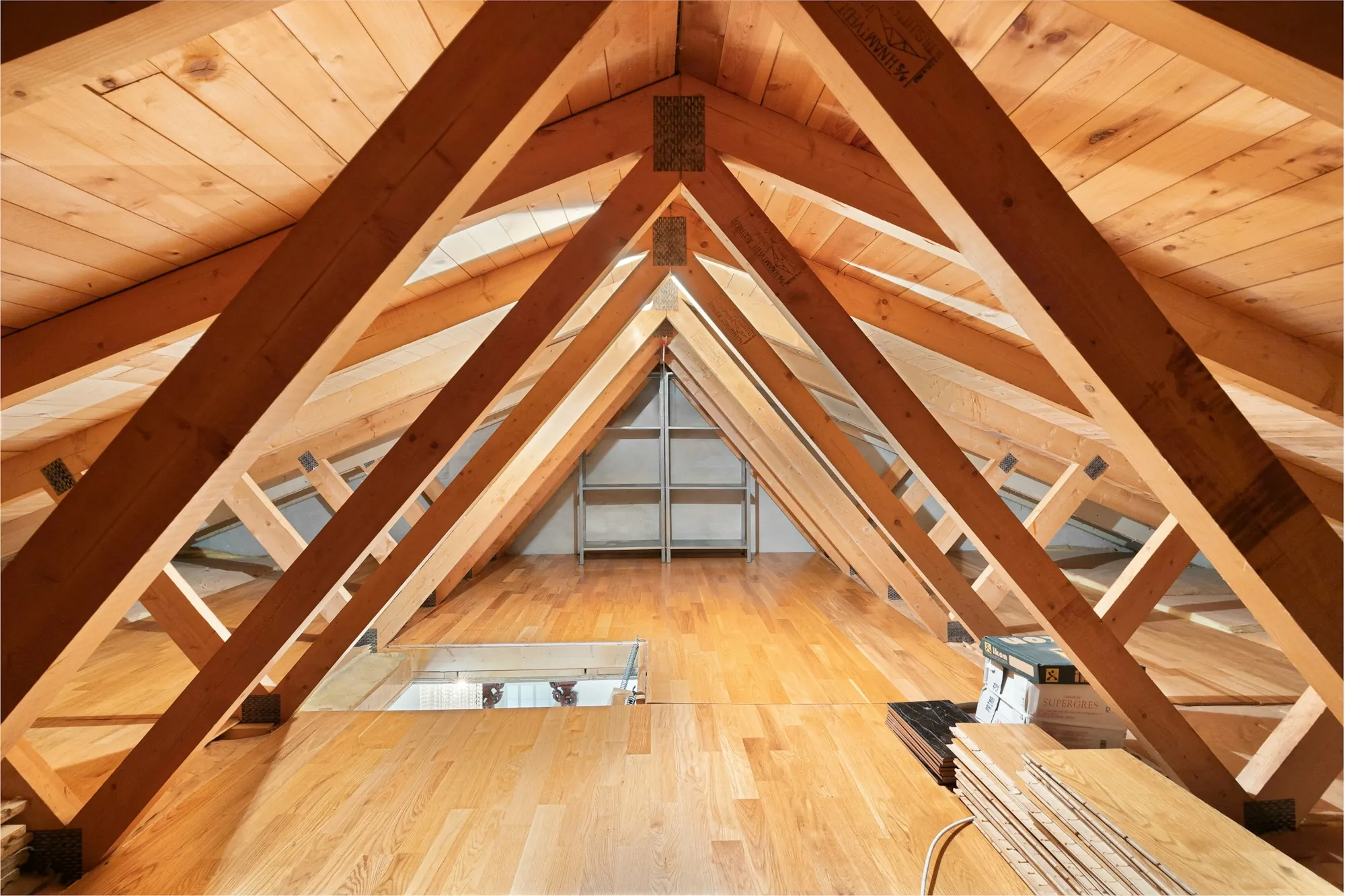 Bright attic space with exposed wood trusses and a pine ceiling