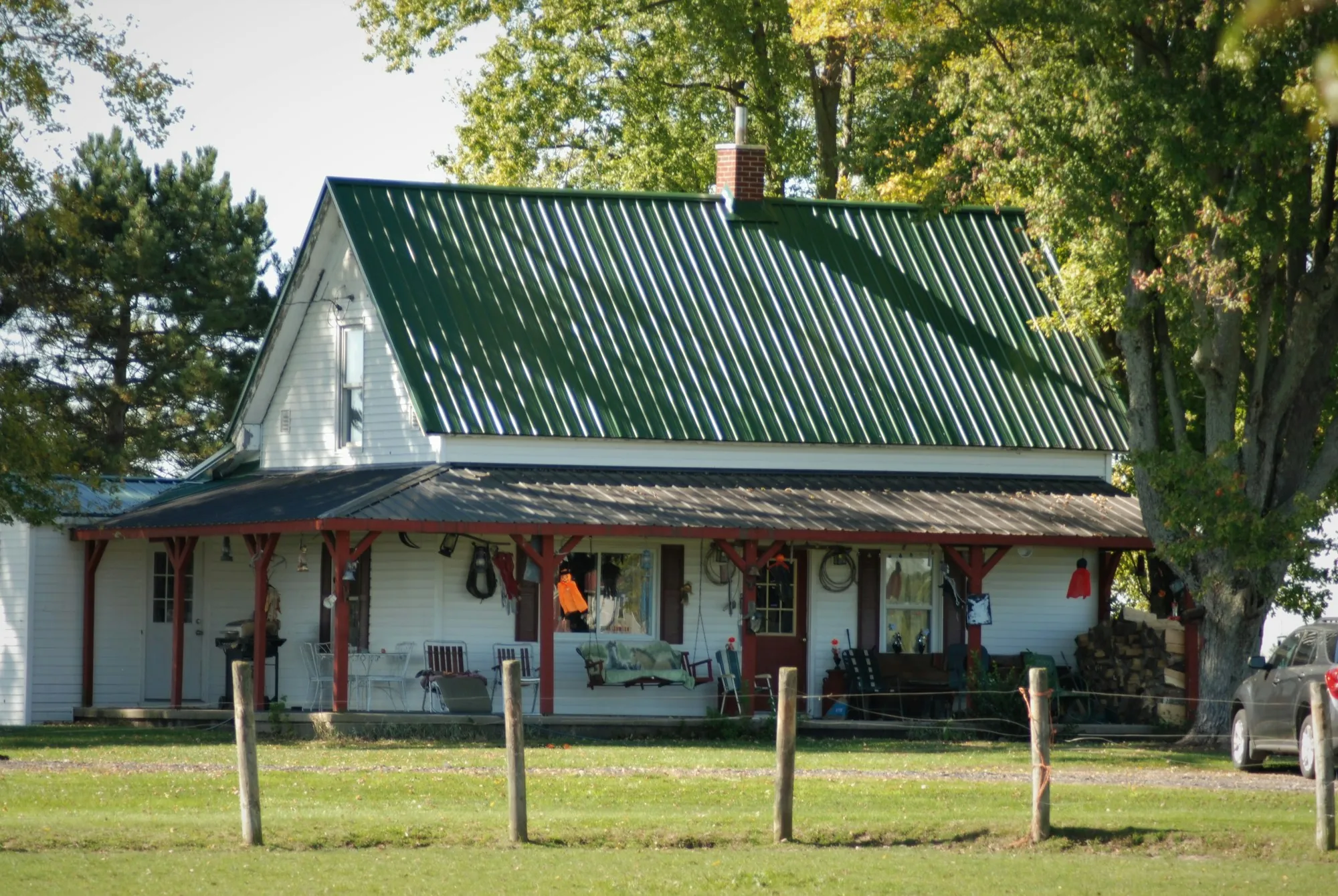 White farmhouse with a green metal roof and a wide front porch