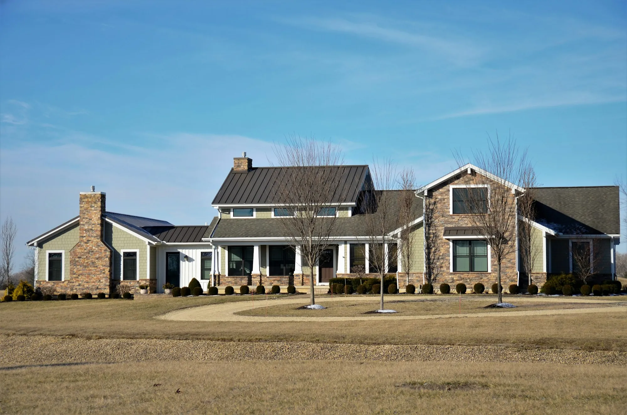 Large stone and siding home with layered shingle rooflines