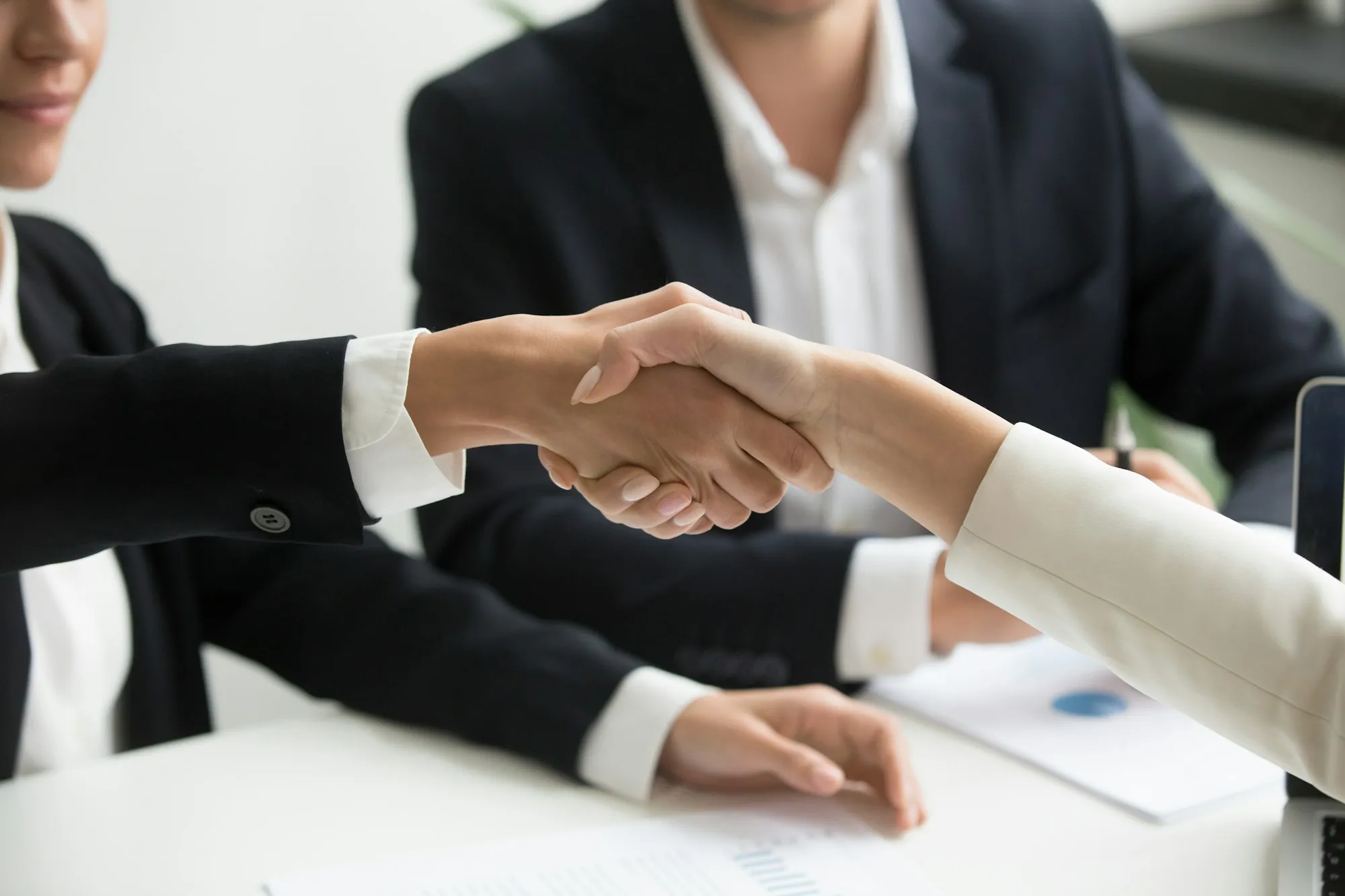 Handshake across a table, standing in for the roof insurance claim process for a Berkeley Lake, Georgia home