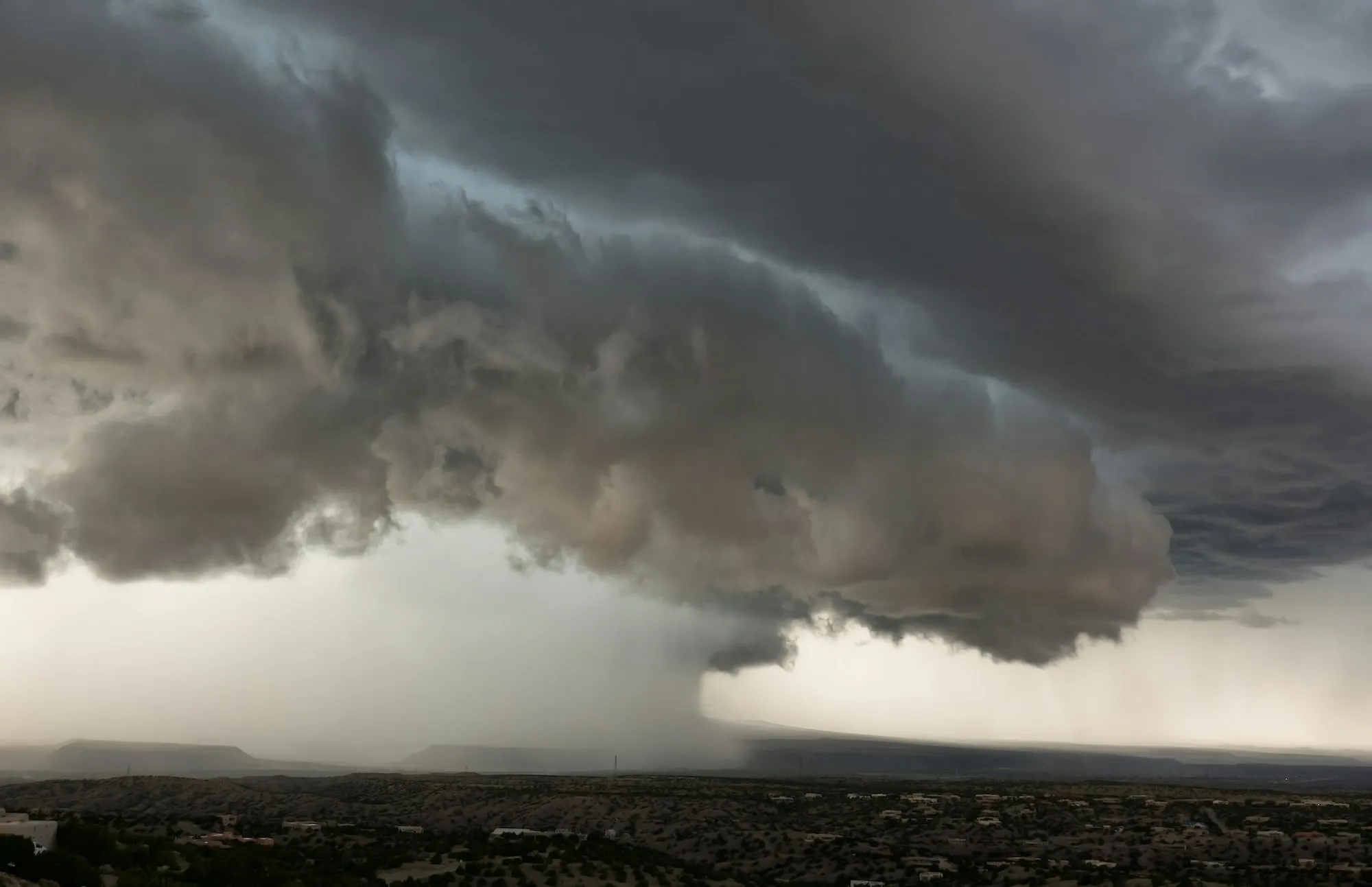 Massive shelf cloud with rain falling over a town