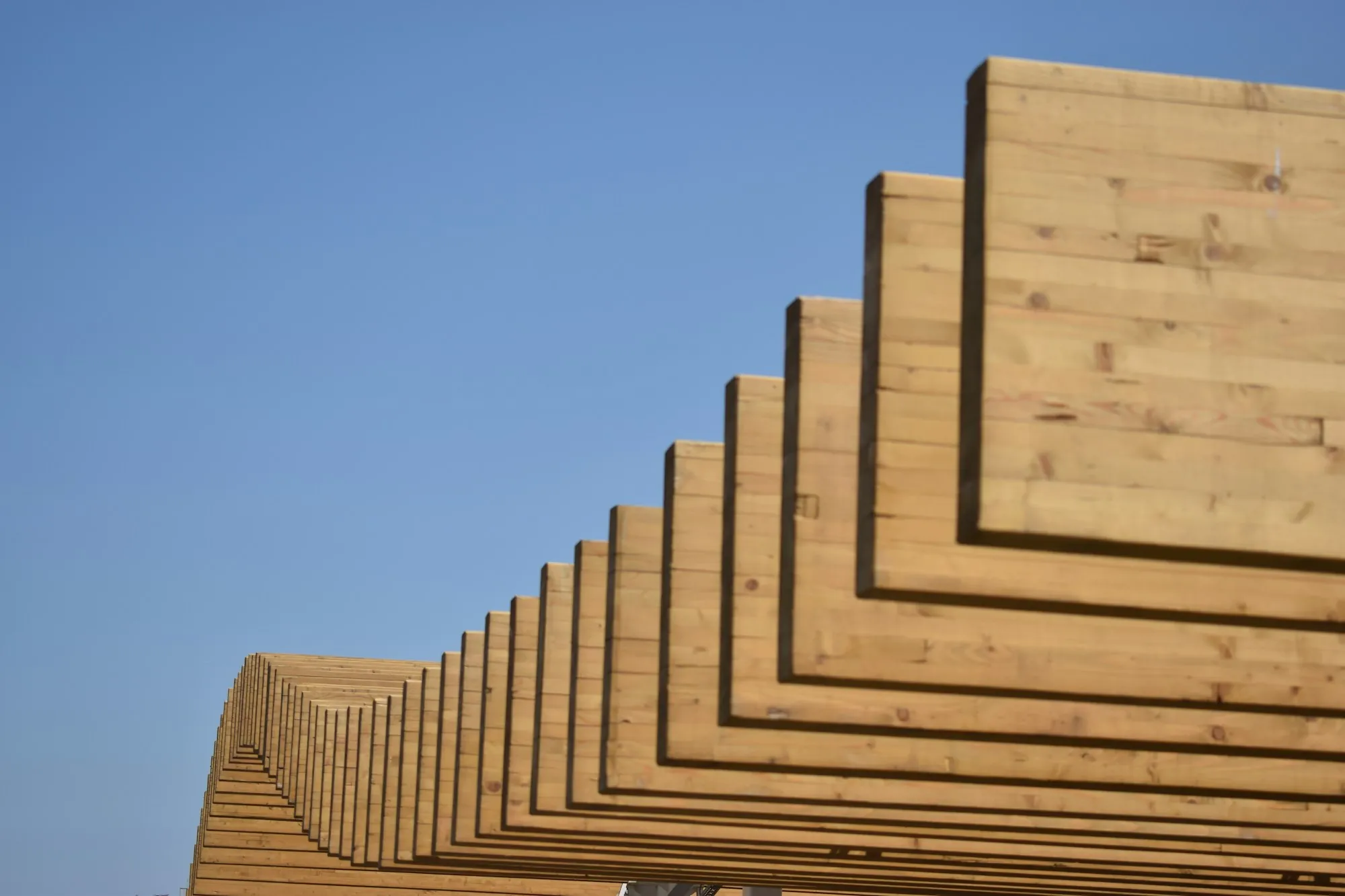Stacked lumber against a clear blue sky